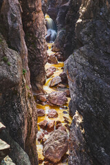 Narrow canyon with fallen boulders and waterfall at end