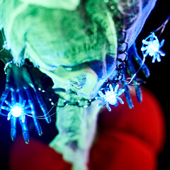 Halloween decoration garland of glowing spiders on the arm of a skeleton