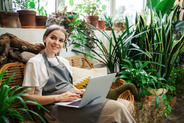 Shop for home plants. A woman sells flowers to a small business. Employee surf the internet information browser.The florist works in the workshop.