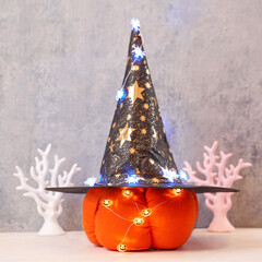 Halloween decoration toy plush pumpkin in a wizard's hat and a garland of glowing spiders