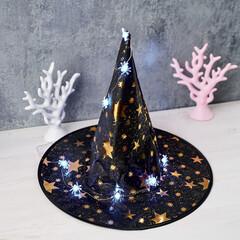 Halloween decoration a wizard's toy hat decorated with a garland of glowing spiders