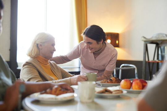 Portrait of smiling young woman caring for senior patient in nursing home, copy space