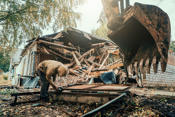 Worker sawing iron at construction site when demolishing house with excavator. Construction...