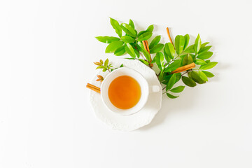 Cup of tea and plant leaves composition on white background. Flat lay, top view. 