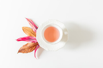 Cup of tea and plant leaves composition on white background. Flat lay, top view. 