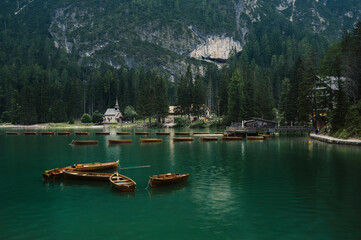 Fototapeta na wymiar Lago di Braies (Braies lake, Pragser wildsee) wooden boats in Lake in South Tyrol, Italy ; moody evening (high ISO photography)