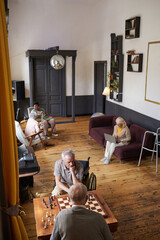 Vertical wide angle shot of senior people enjoying activities in nursing home, copy space