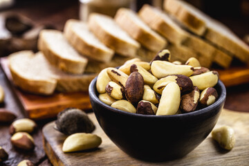 bowl of Brazil nuts with vegan whole grain bread in the background, healthy vegan cooking ingredient, exotic nut