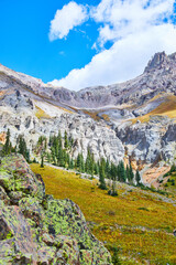 Naklejka premium Beautiful mountain range in Colorado with rocks covered in lichen and grey mountain peaks against blue sky and clouds