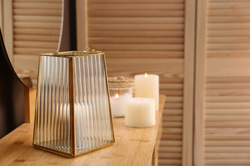 Stylish holder with burning candle on wooden table indoors. Space for text