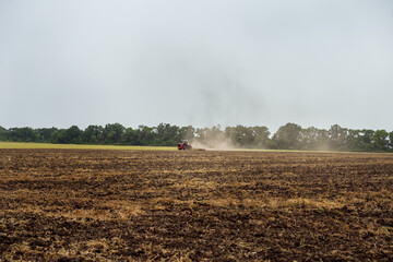 Fototapeta premium The tractor plows the field against the background of the sky. Harvesting in the field. Autumn work on the farm. Mechanized work. Modern farming.