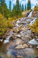 Vertical of waterfall cascading down gray rocks in valley