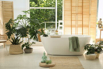 Stylish bathroom interior with modern tub and beautiful houseplants