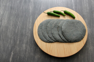 Fresh, delicious, freshly made blue crust tortillas in basket, cutting board and red napkin with...