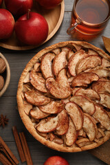Delicious apple pie, ingredients and cup of tea on wooden table, flat lay