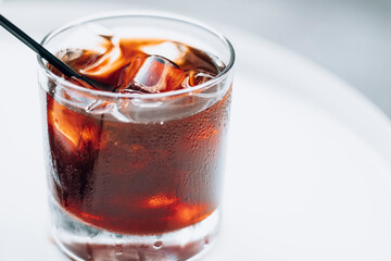 Cold brew with full of ice and black straw on a white background. Delicious cold beverage with coffee.
