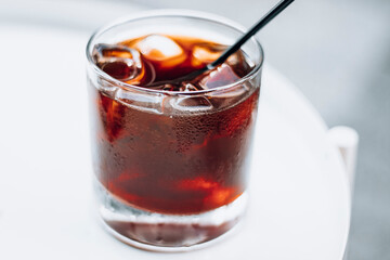 Cold brew with full of ice and black straw on a white background. Delicious cold beverage with coffee.