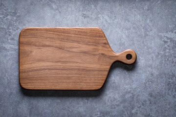 Handmade black walnut wooden cutting board on cement textured tabletop. Walnut wooden chopping board. Walnut chopping board background element.