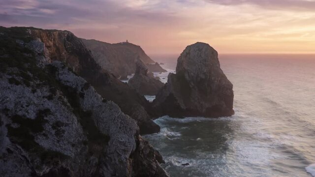 Drone footage of wild place with rare beauty of the sea. Sharp scarps between cliffs and many rocks brought by the ocean as seen from top. Europe, Portugal, Sintra, Ursa Beach. High quality 4k footage
