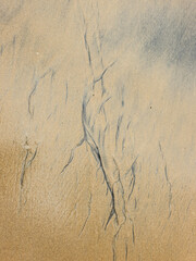 Patterns on the beach formed by the waves lapping the sand.