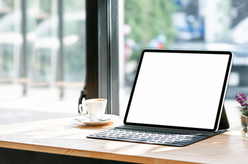 Mockup white screen tablet with keyboard and coffee cup on wooden counter table.