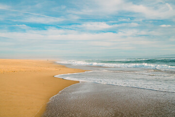 Fototapeta na wymiar Wide sandy beach, blue sea, and beautiful cloudy sky.