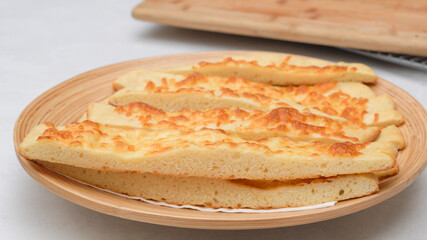 Delicious homemade flat bread with mozzarella cheese topping close up on wooden plate
