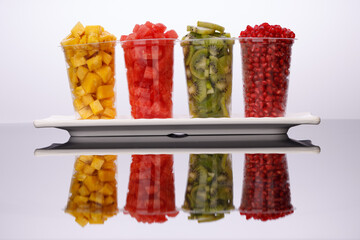 Watermelon , pineapple  , pomegrenate and Kiwi  Slices arranged  in two transparent glasses with white background, isolated