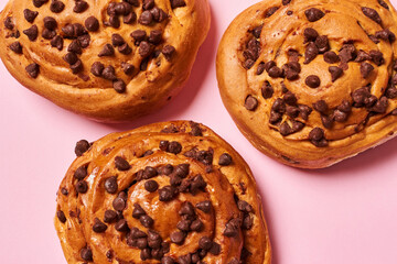 Close up of sweet roll breads with chocolate chips on pink background. Horizontal photo. Top view angle. Food and healthy concepts.