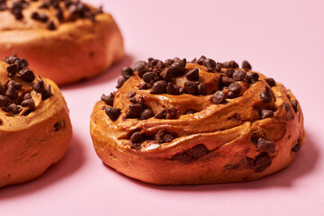Close up of sweet roll breads with chocolate chips on pink background. Horizontal photo. Top view angle. Food and healthy concepts.