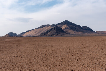 malek mohammad mountain in dasht e lut desert with cloudy sky and gravel ground in foreground in iran