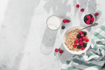 Breakfast bowl with granola, muesli, raspberry, blackberry on gray table