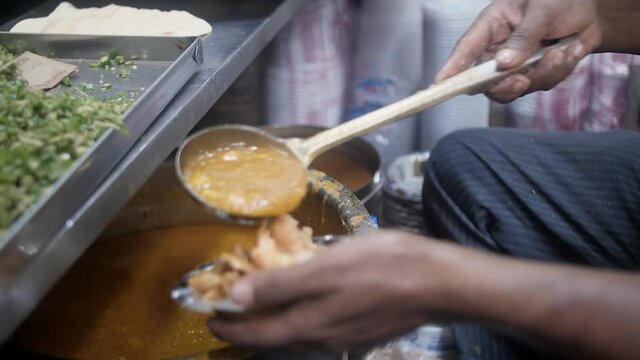 A street vendor is serving hot Kachori with Sabzi. Fresh hot Kachuri served with potato curry in a small shop in a famous Indian market - morning breakfast  street food  deep fried