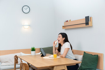 Living room concept a female adult enjoying eating sandwiches and orange juice watching online...