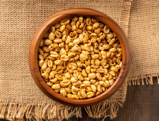Wheat flakes cereal breakfast in wooden bowl with dry spikelets on the rustic background. Selective focus.