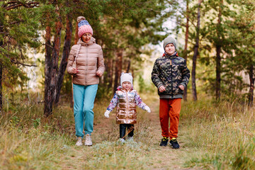 Naklejka na ściany i meble children and an elderly woman run along path in the woods in the fall