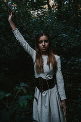 girl in a historical dress in a coniferous forest