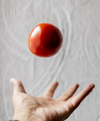 Hand throwing tomato with white textured wall as background