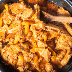 Cooking Thai style pork curry with pepper in a pan - top view, close-up