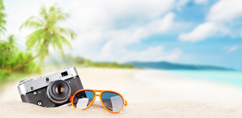 Retro camera and sunglasses on tropical beach