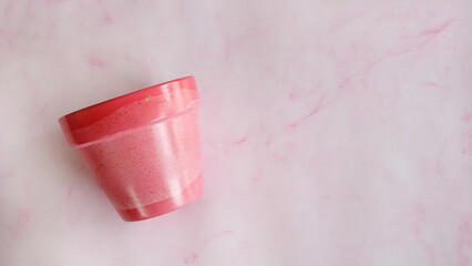 Flat lay of a terracotta pot painted in pink acrylic paint. With copy space on the right and pink background.