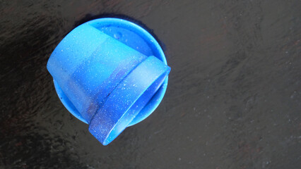 Top view of a flower pot painted in blue gradient. On a wooden surface with copy space on the right .