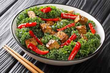 Vegetarian organic food tofu salad with bell peppers, kale and sesame seeds close-up in a bowl on the table. horizontal