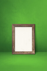 Wooden picture frame leaning on a green wall