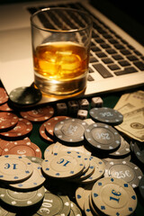 Poker chips, glass of beverage, dices and laptop on table in casino