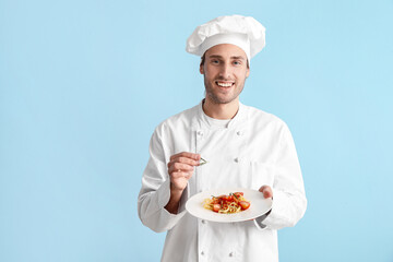 Handsome chef with tasty pasta and rosemary on blue background
