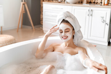 Young woman with facial mask taking relaxing bath at home