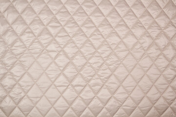 Quilted fabric. The texture of the blanket. Beige textiles	
