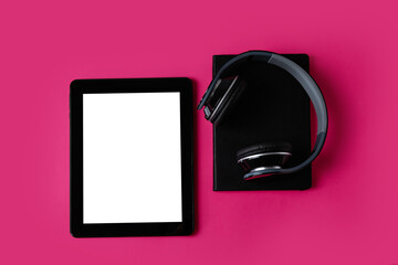 Modern tablet computer, headphones and notebook on color background