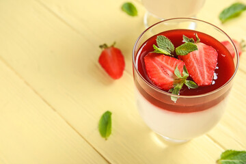 Glass with tasty strawberry panna cotta on color wooden background, closeup